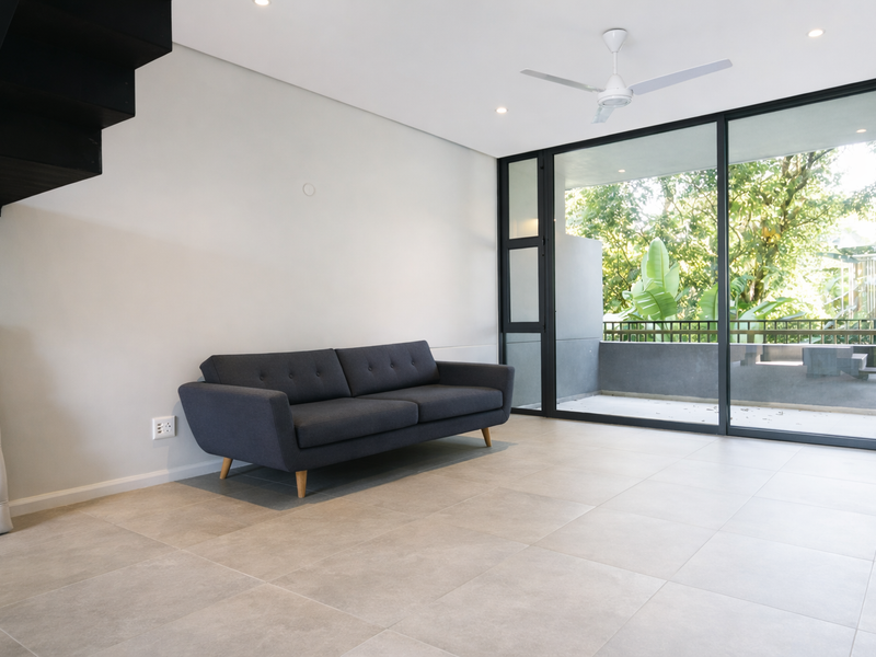 Modern living area featuring large sliding glass doors leading to a balcony, neutral tiled flooring, recessed lighting, and a ceiling fan.