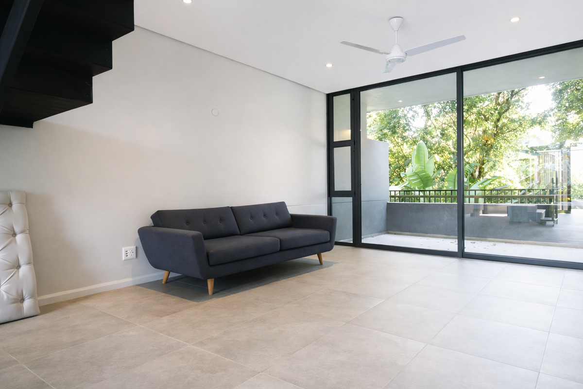 Modern living area featuring large sliding glass doors leading to a balcony, neutral tiled flooring, recessed lighting, and a ceiling fan.