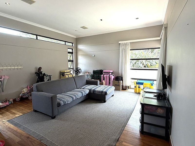 Spacious living room featuring hardwood flooring, recessed downlighting, and large windows that provide ample natural light.