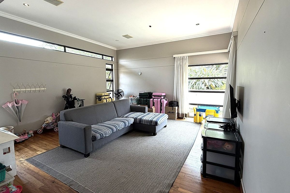 Spacious living room featuring hardwood flooring, recessed downlighting, and large windows that provide ample natural light.