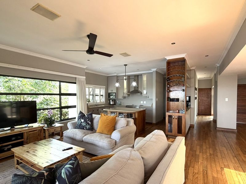 Spacious open-plan living area featuring hardwood floors, a modern kitchen with an island, and large windows providing ample natural light.