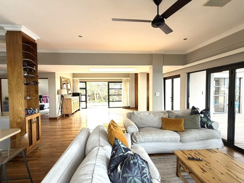 Spacious open-plan living area featuring hardwood floors, a ceiling fan, recessed lighting, and large sliding glass doors that provide seamless access to the outdoor deck.