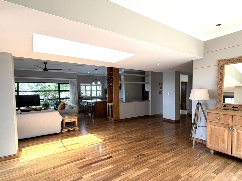 Spacious open-plan living area featuring polished hardwood flooring, a large skylight, and a seamless transition into the kitchen and dining space.