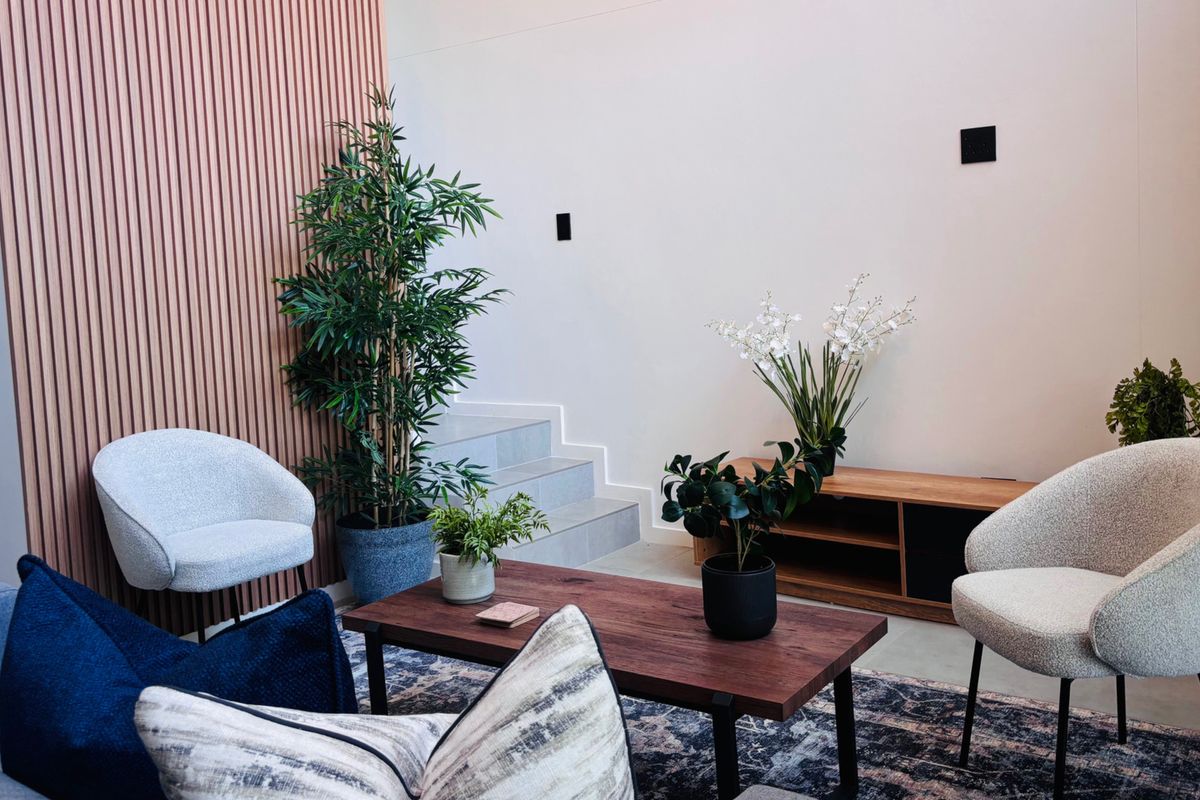 A modern living area featuring a stylish slatted timber feature wall and a staircase with tiled treads, creating a contemporary and inviting atmosphere.