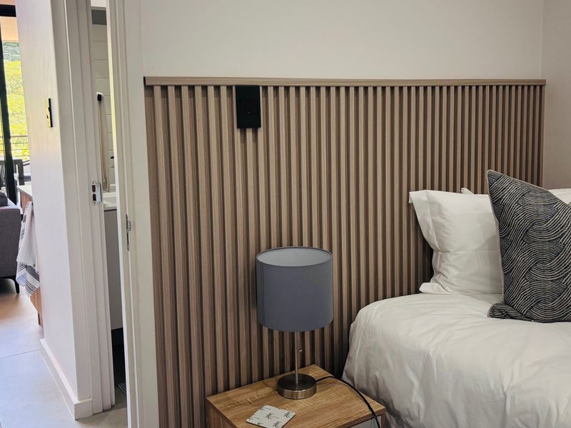 A modern bedroom featuring a stylish timber slat feature wall, providing a contemporary aesthetic and warm texture to the sleeping space.