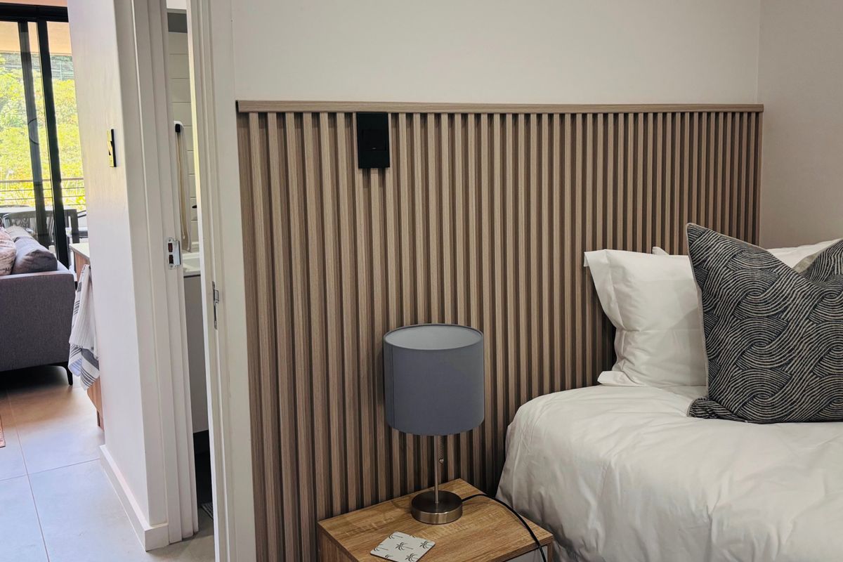 A modern bedroom featuring a stylish timber slat feature wall, providing a contemporary aesthetic and warm texture to the sleeping space.