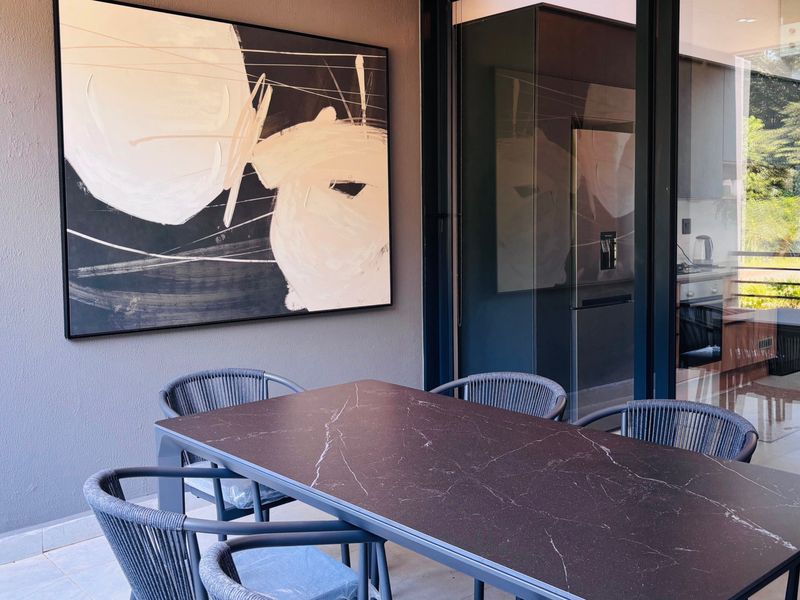 A modern covered patio area featuring sleek tiled flooring and large sliding glass doors that provide a seamless transition to the interior living space.