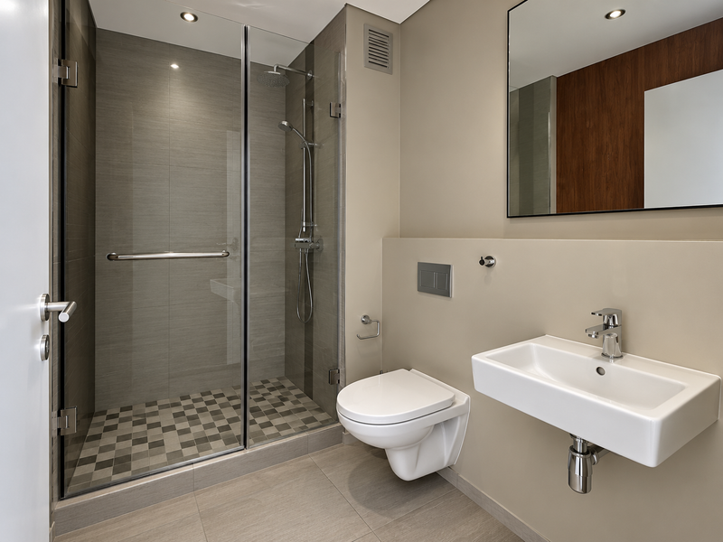 Modern bathroom featuring a glass-enclosed shower, wall-mounted toilet, and sleek wall-mounted basin with contemporary finishes and recessed lighting.