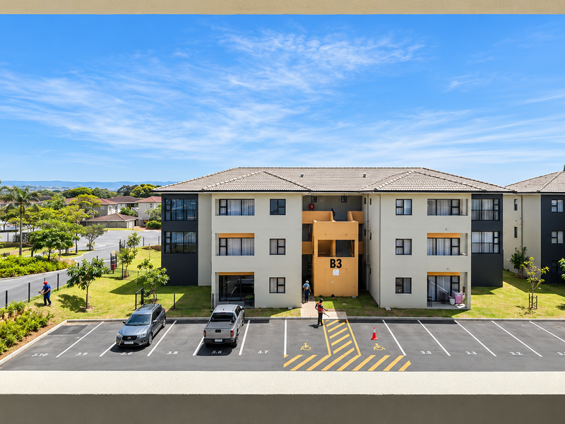 A clear elevated view overlooking a residential apartment complex with a paved parking area and landscaped grounds.
