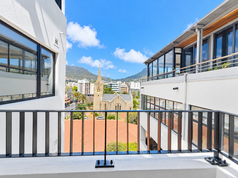 A clear view of the surrounding urban landscape and historic church from a modern apartment balcony with sleek metal railings.
