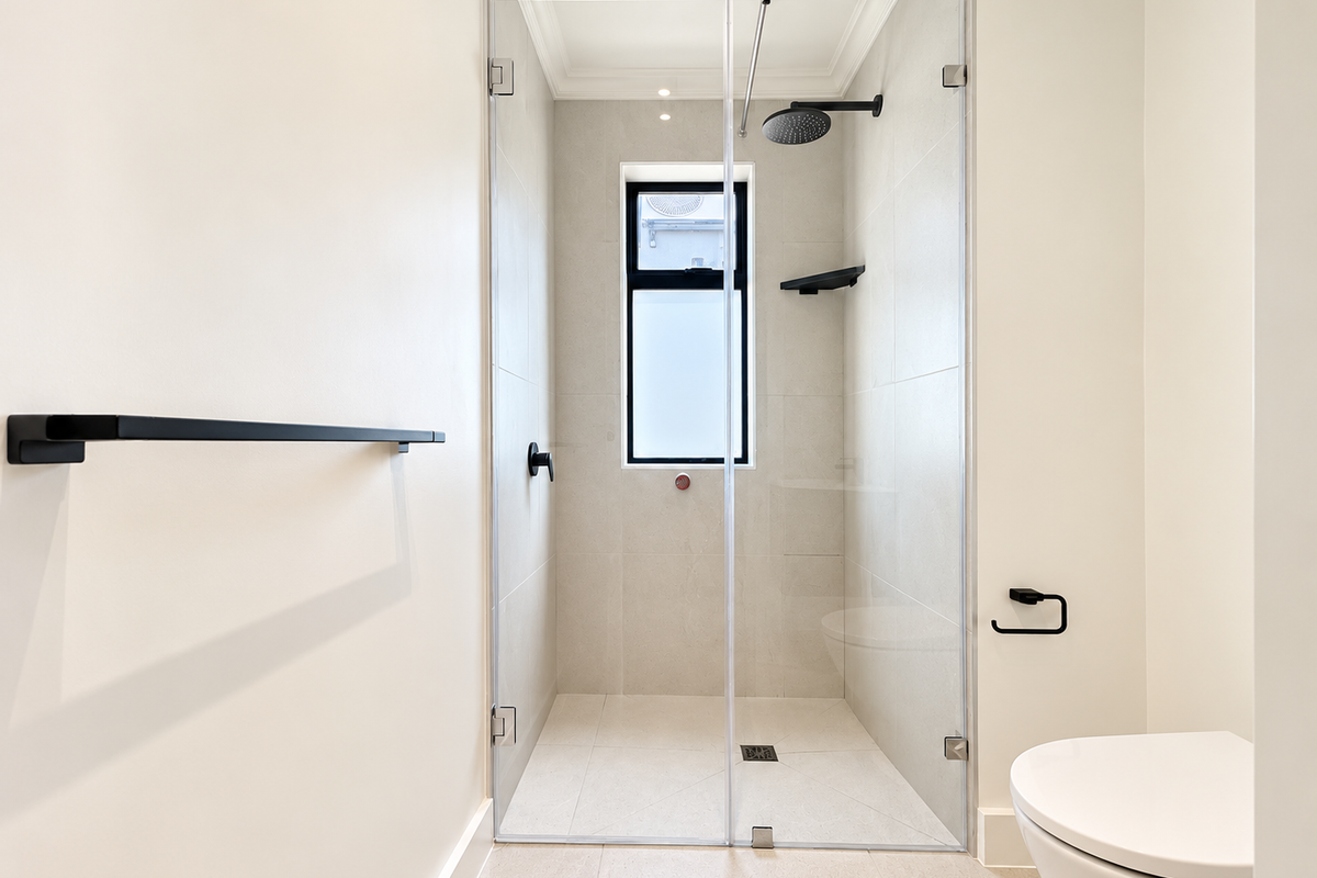 Modern bathroom featuring a spacious walk-in shower with a rain shower head, glass screen, and contemporary matte black fixtures.