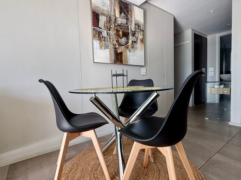 A modern dining area featuring neutral tiled flooring and recessed downlighting, creating a clean and contemporary living space.