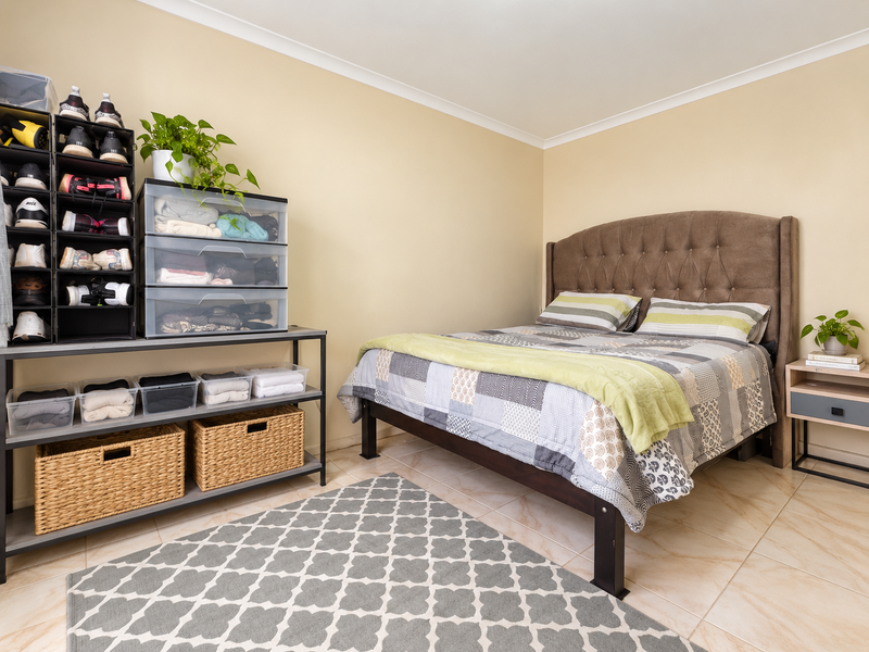 A bedroom featuring neutral wall paint, tiled flooring, and a coved ceiling, providing a functional and well-maintained living space.