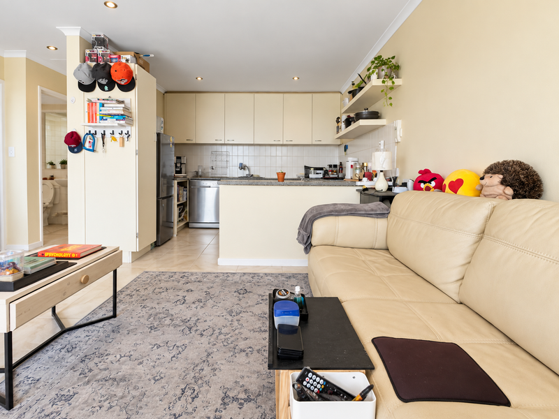 Open plan living area featuring a functional kitchen with built-in cabinetry, stone countertops, and tiled backsplash, seamlessly connected to the lounge space.