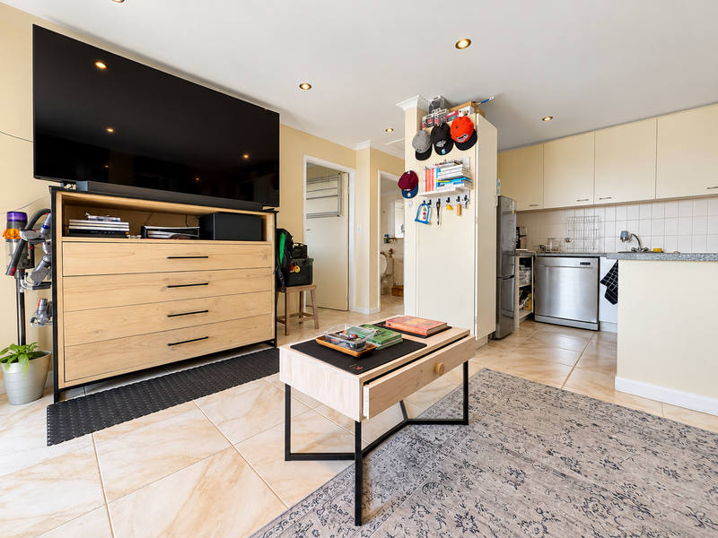 Open-plan living area featuring tiled flooring, recessed lighting, and a functional kitchen with integrated cabinetry and appliances.