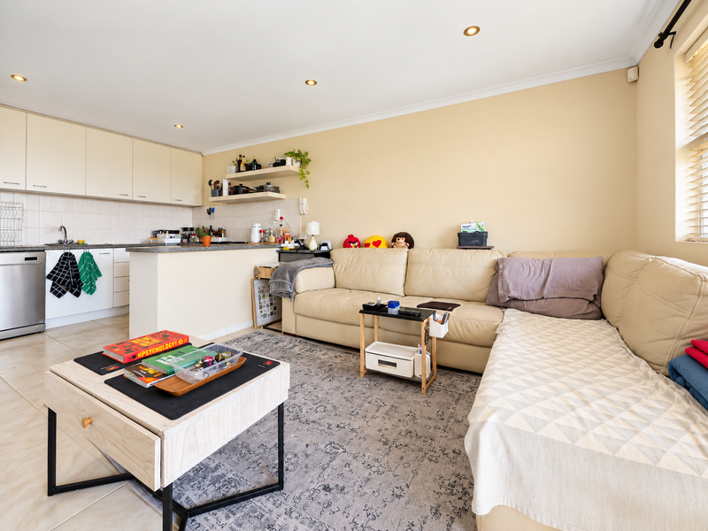 Open-plan living area featuring a functional kitchen with built-in cabinetry, integrated dishwasher, and a breakfast counter, seamlessly flowing into the lounge space.