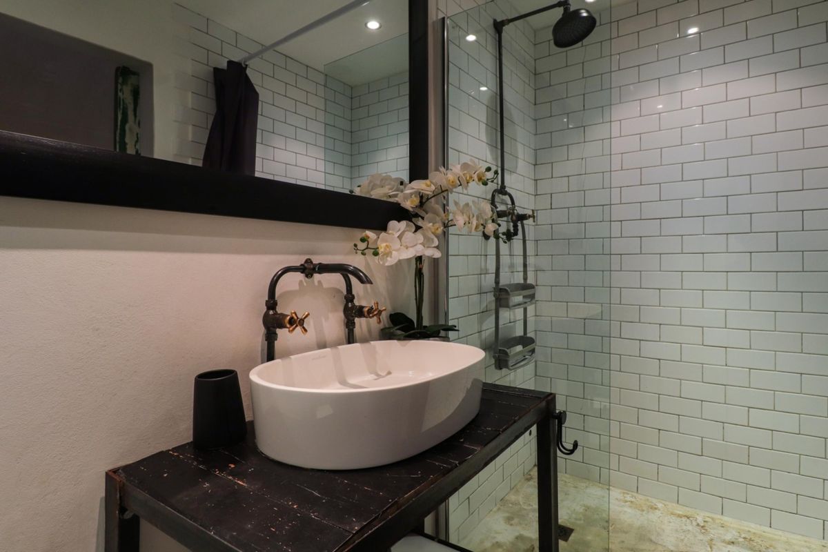 Modern bathroom featuring a subway-tiled shower enclosure, vessel sink with vintage-style fixtures, and a large wall-mounted mirror.