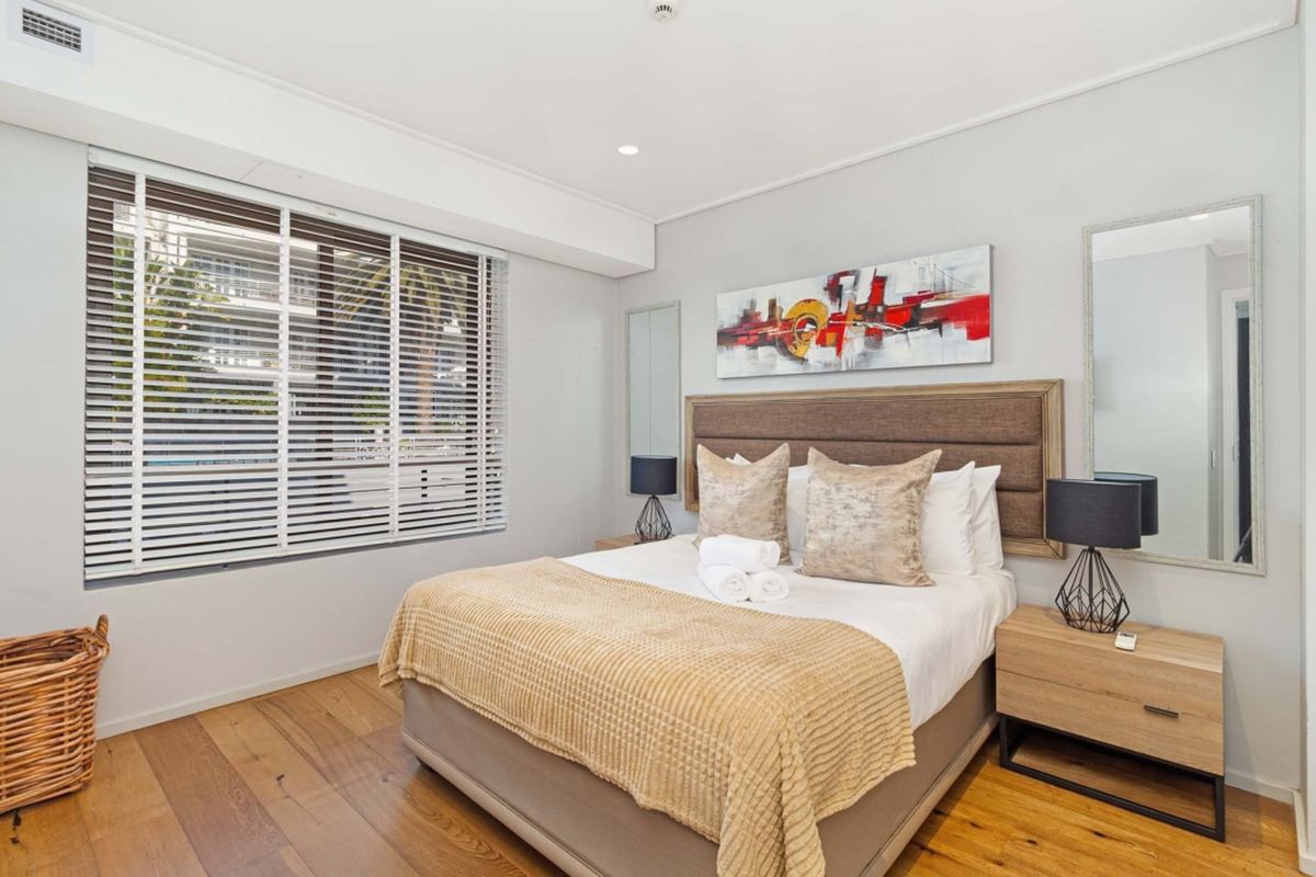 A well-maintained bedroom featuring hardwood flooring, recessed lighting, and venetian blinds, offering a clean and comfortable living space.