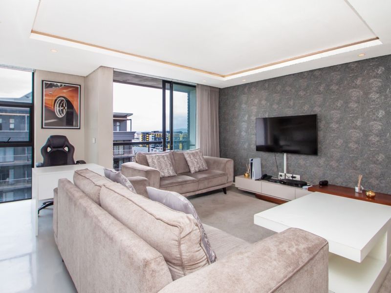 Modern living room featuring a recessed ceiling with downlights, textured feature wall, and large sliding glass doors leading to a balcony.