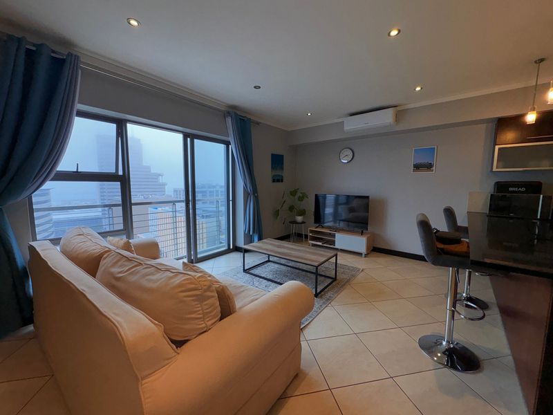 Open-plan living area featuring tiled floors, recessed lighting, a split-system air conditioner, and direct access to a balcony with city views.