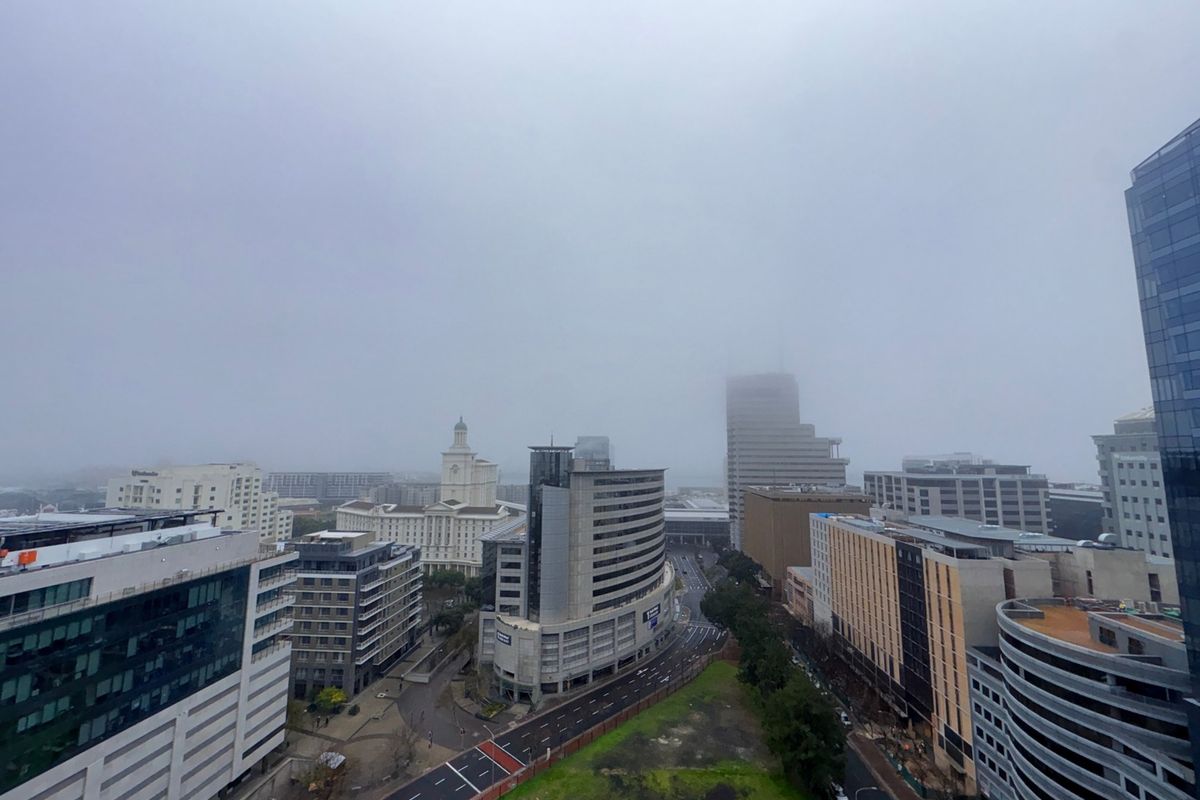 An elevated city skyline view captured from an apartment balcony on a cloudy day.