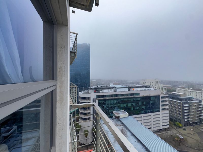 An elevated urban view from a balcony looking out over surrounding city buildings and commercial infrastructure.