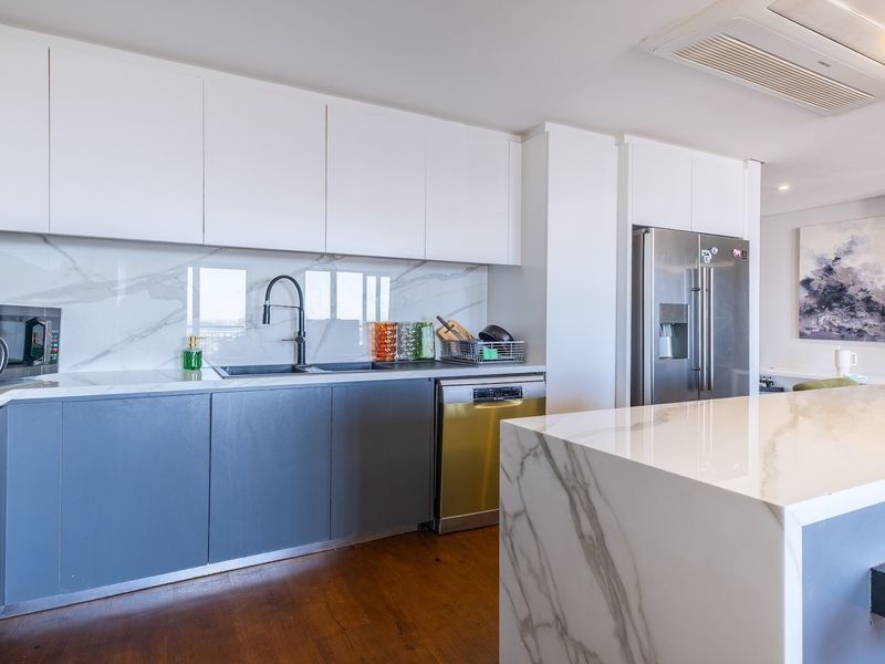 Modern kitchen featuring marble-look stone countertops and backsplash, sleek cabinetry, integrated appliances, and high-quality finishes throughout.