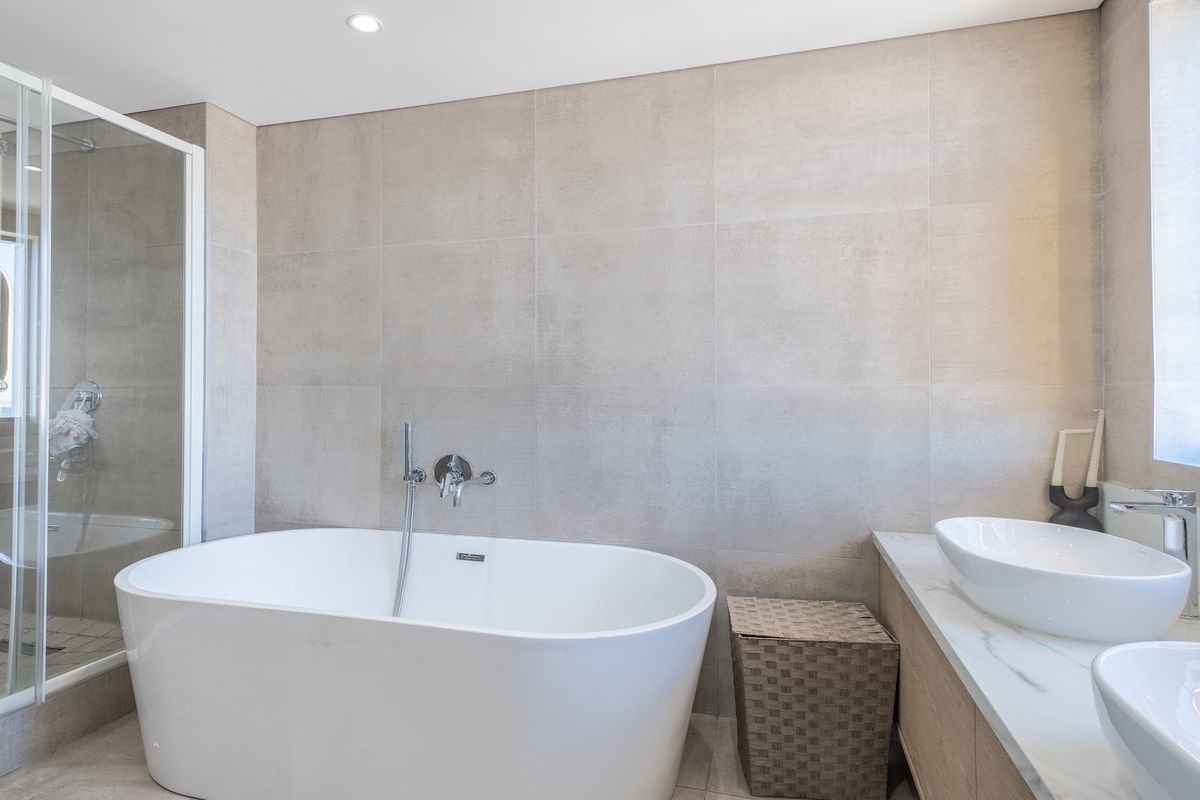 Modern bathroom featuring a freestanding bathtub, a separate walk-in shower with glass enclosure, and a double vanity with vessel sinks and marble-look countertop.
