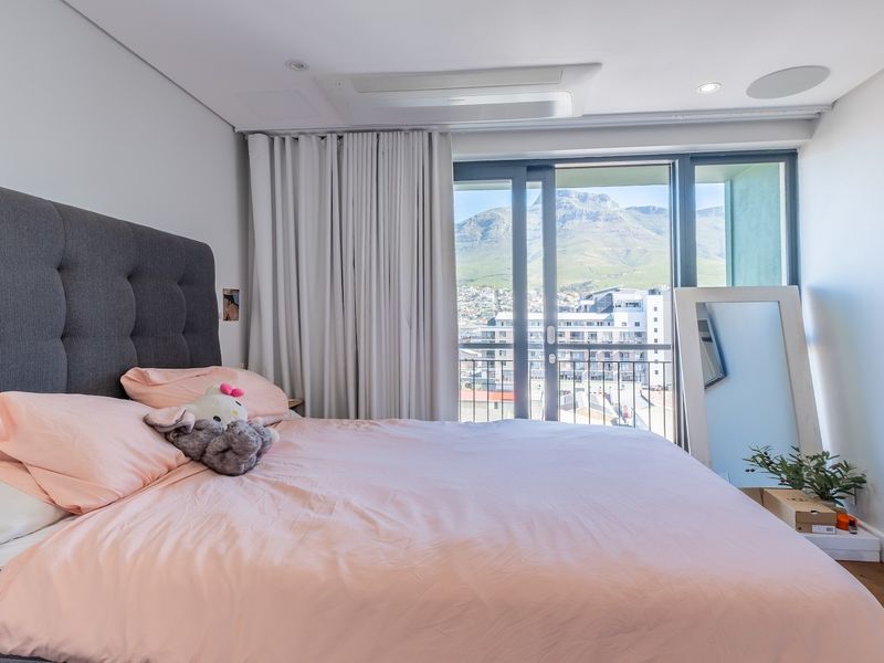 Modern bedroom featuring a large sliding glass door with balcony access, integrated ceiling speakers, and a built-in air conditioning unit with mountain views.