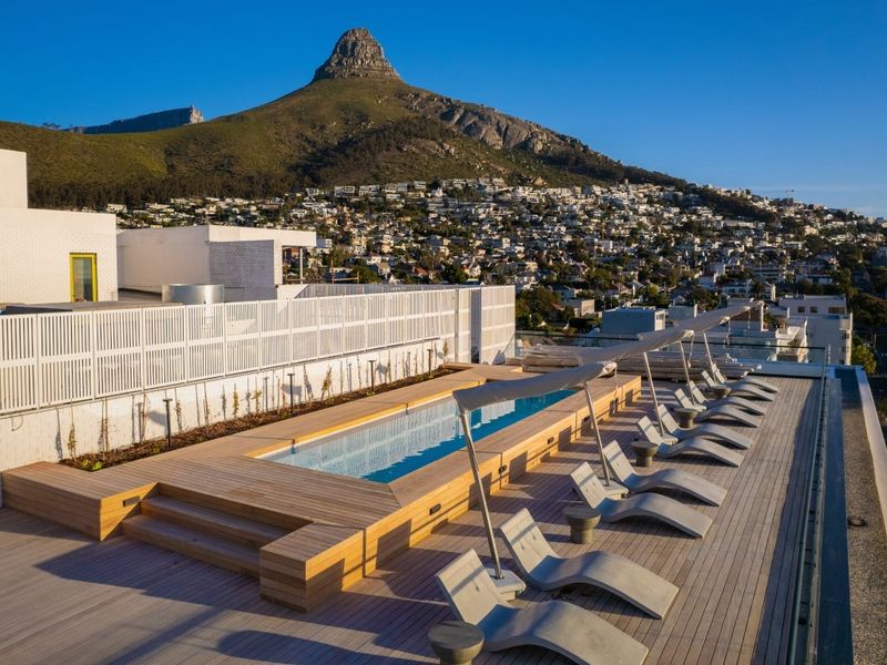 Rooftop swimming pool area featuring timber decking and panoramic mountain views, providing a premium outdoor leisure space.