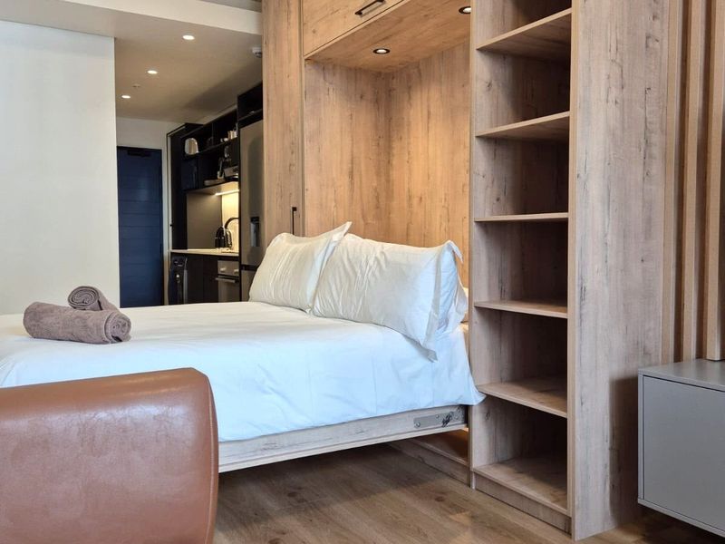 Modern open-plan studio apartment featuring high-quality built-in cabinetry, integrated shelving, and a compact kitchenette with contemporary finishes.
