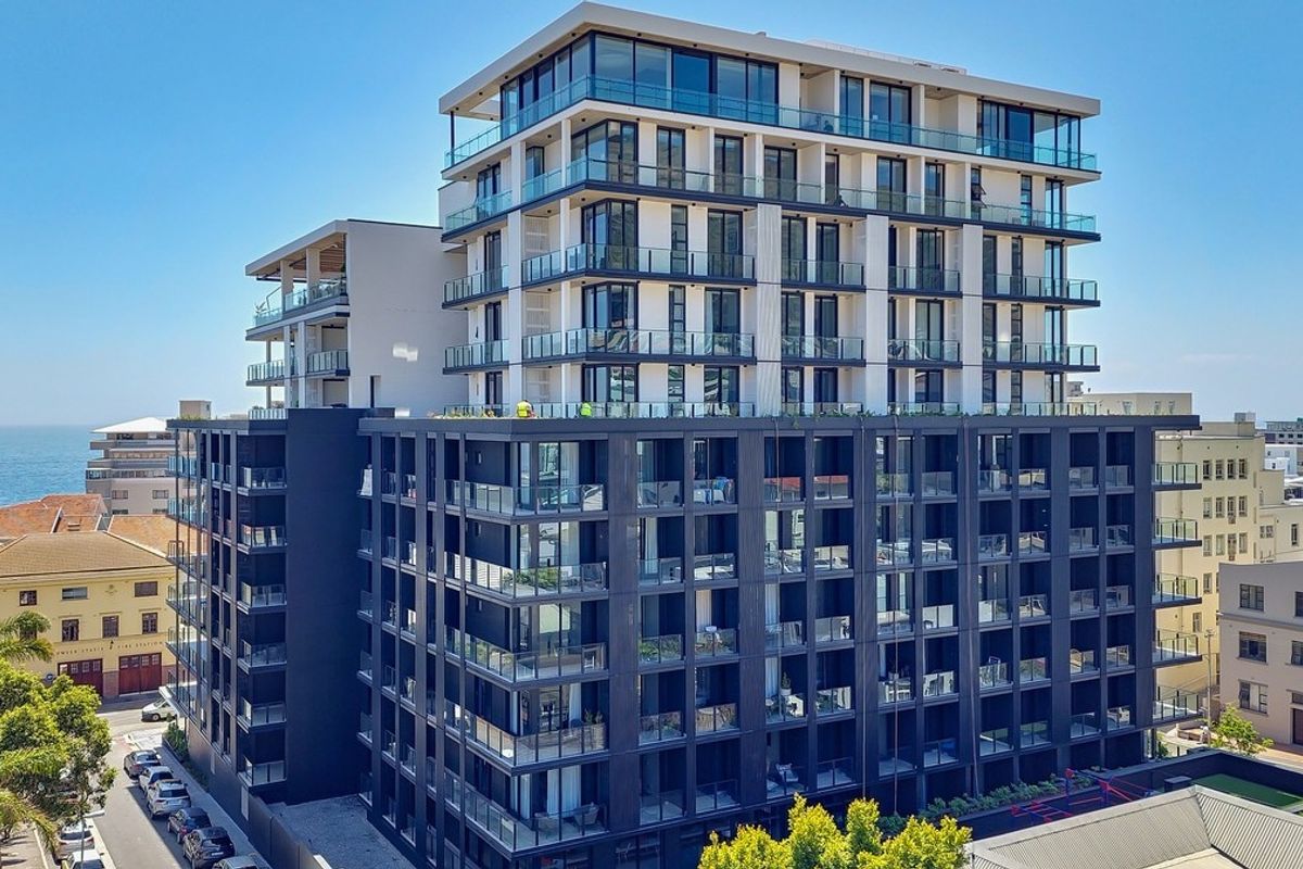 Aerial view of a modern multi-story apartment building featuring contemporary architecture, glass balconies, and a sleek dark exterior finish.