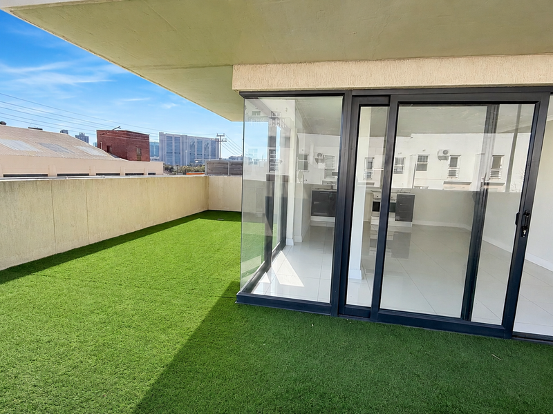 Spacious balcony featuring artificial grass flooring and large sliding glass doors providing seamless access to the interior living area.