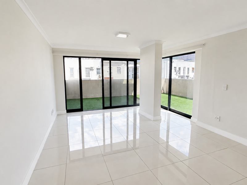 Bright and spacious open-plan living area featuring polished porcelain floor tiles and large sliding glass doors leading to an outdoor balcony space.