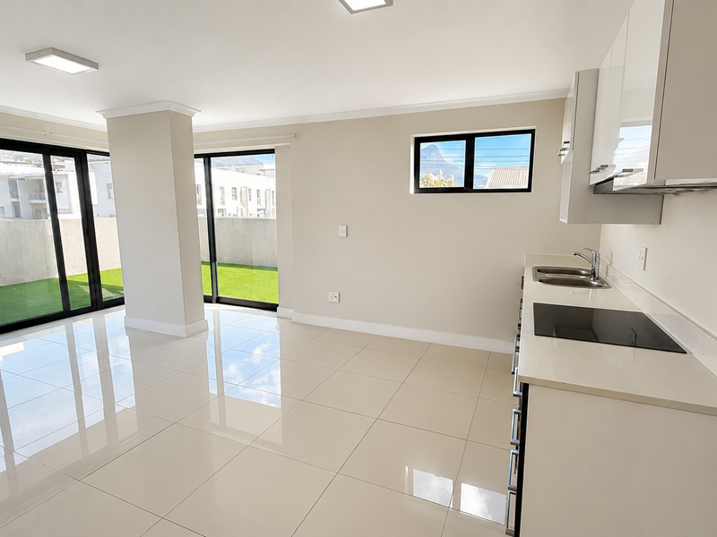 Modern open-plan kitchen and living area featuring sleek cabinetry, quartz countertops, electric hob, and large sliding doors opening to a private patio.