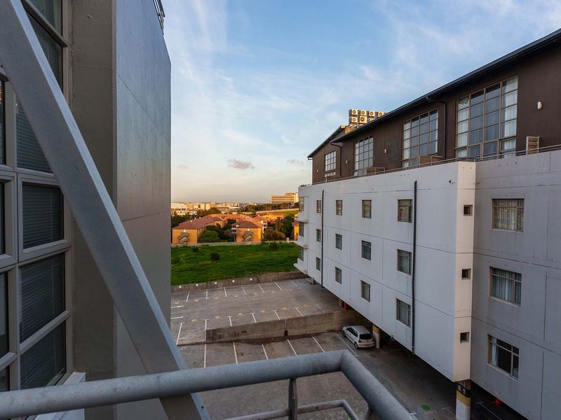 An elevated view from a balcony overlooking the apartment complex parking area and surrounding neighborhood landscape.