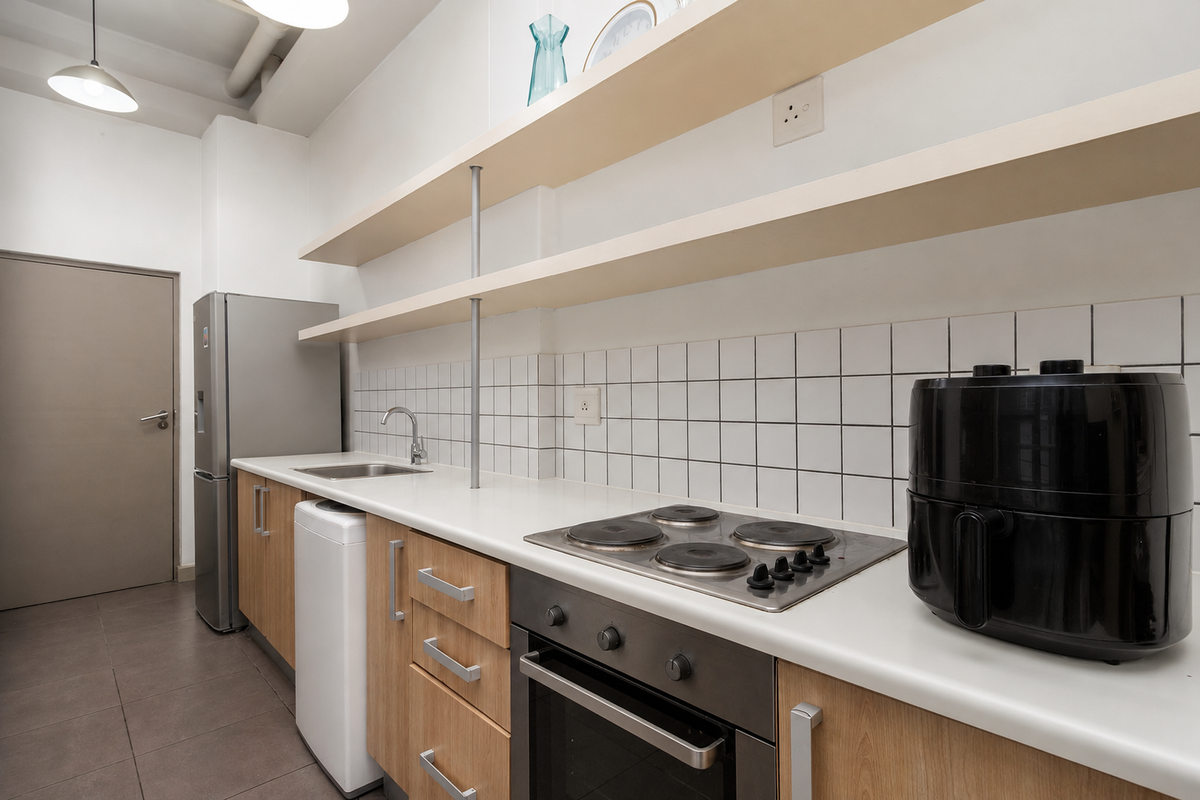 A functional kitchen featuring light wood cabinetry, open shelving, a tiled backsplash, and integrated electric cooking appliances.
