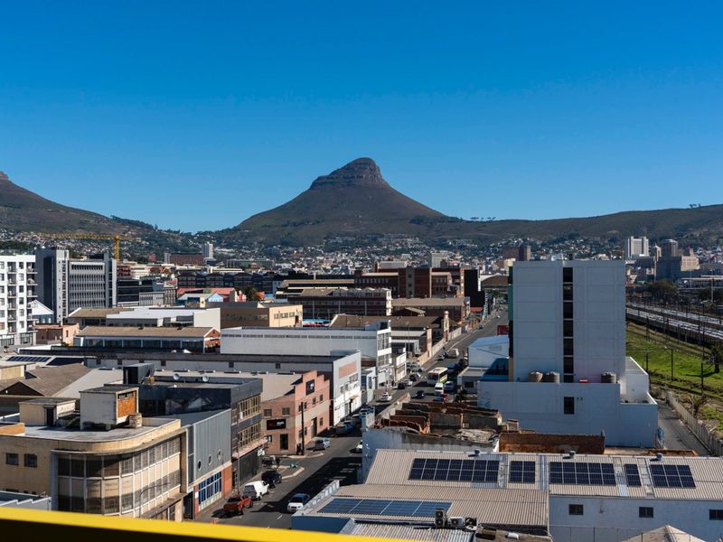 Elevated urban view overlooking the city skyline with a prominent mountain backdrop and clear blue sky.