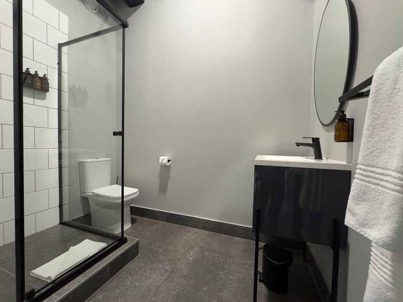 Modern bathroom featuring a walk-in shower with black frame, vanity cabinet with basin, and contemporary tiled finishes.