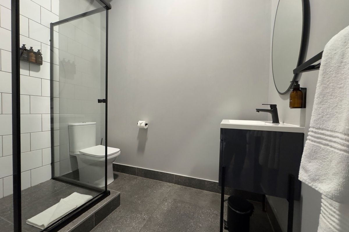 Modern bathroom featuring a walk-in shower with black frame, vanity cabinet with basin, and contemporary tiled finishes.