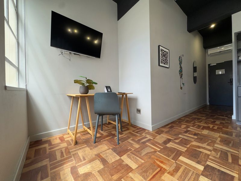 A functional office space featuring parquet flooring, a wall-mounted television, and an integrated air conditioning unit.