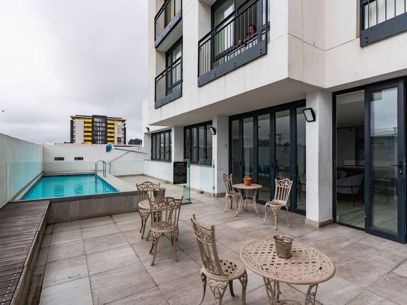 A spacious outdoor patio area featuring a private swimming pool, glass balustrades, and direct access to the apartment interior through large sliding glass doors.