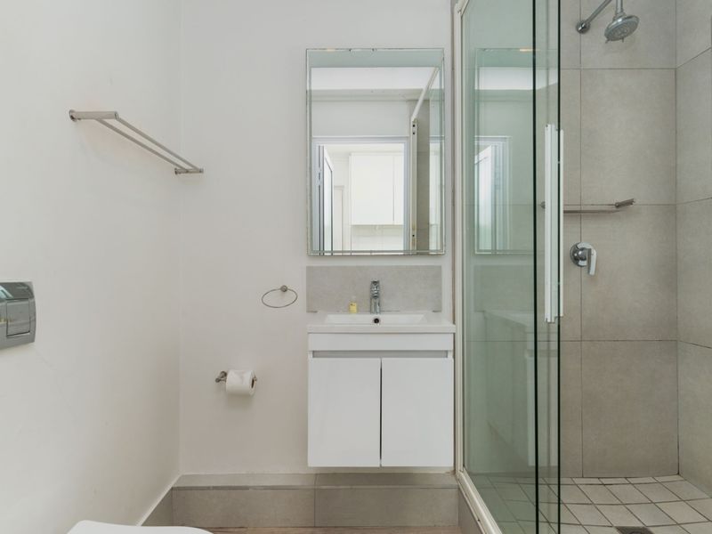 A clean, modern bathroom featuring a wall-mounted vanity, glass-enclosed shower with tiled finishes, and contemporary fixtures.