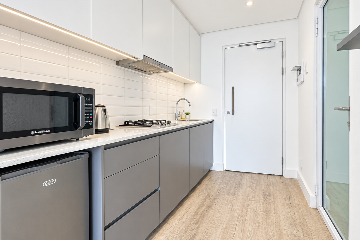 Modern galley kitchen featuring sleek grey and white cabinetry, quartz countertops, gas hob, integrated extractor, and stylish subway tile backsplash.