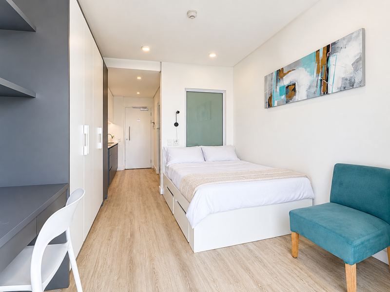 A modern, well-maintained bedroom featuring built-in cabinetry, a built-in desk, laminate flooring, and recessed lighting, with a clean and contemporary aesthetic.