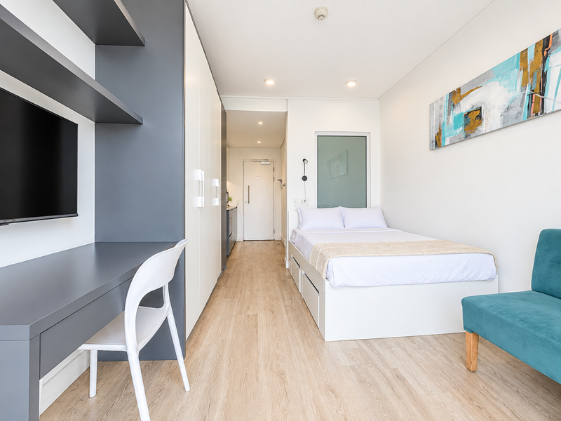 Modern bedroom featuring light wood-look laminate flooring, built-in cabinetry with integrated desk space, and recessed ceiling lighting.