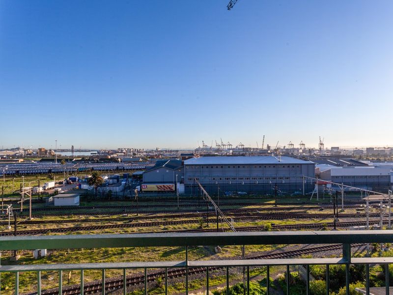 An elevated view from a balcony overlooking a railway yard and industrial port area.