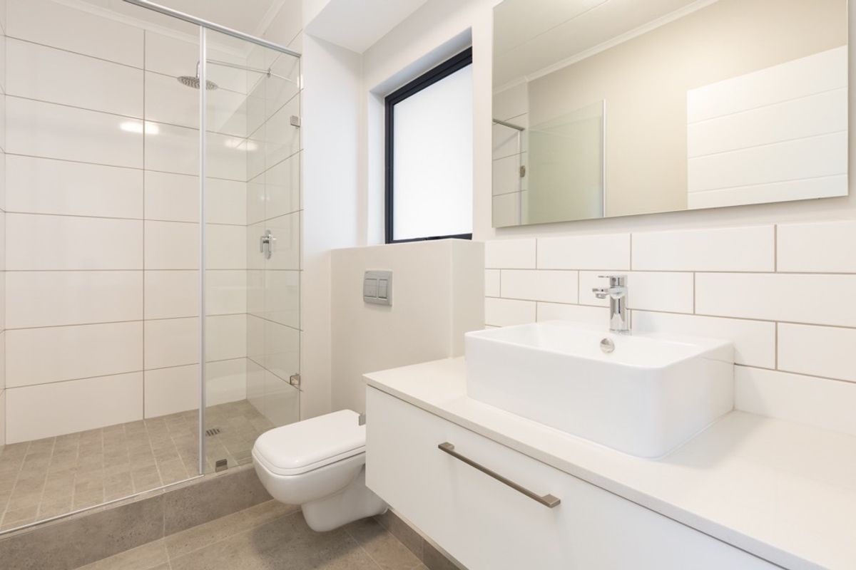 Modern bathroom featuring a walk-in shower with glass screen, floating vanity with vessel sink, wall-mounted toilet, and clean white subway tile finishes.