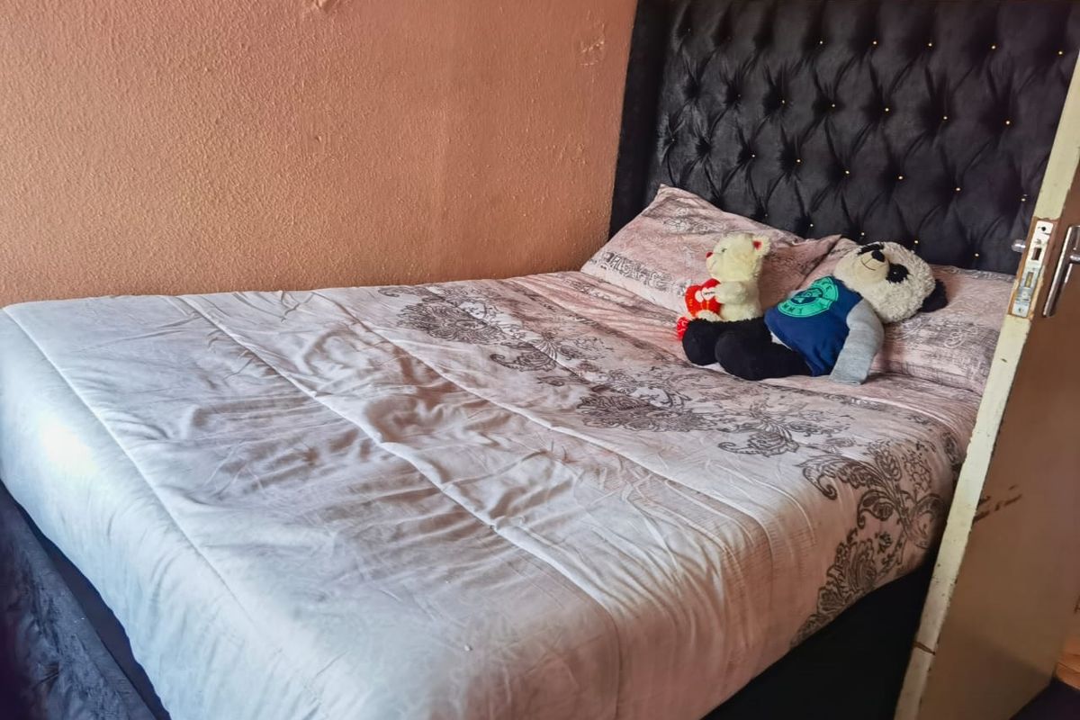 A bedroom featuring a tufted headboard and textured wall finish, requiring minor cosmetic repairs to the wall surface.