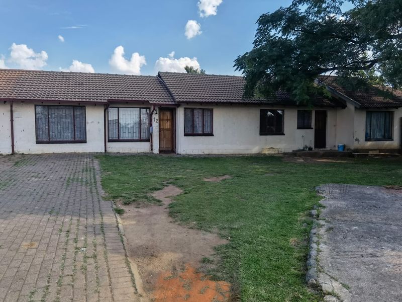 A single-story residential property featuring a tiled roof, paved driveway, and a front garden area with security bars on windows.